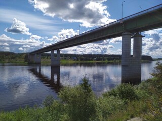 A long high concrete bridge over a wide calm river Suhona ,Russia