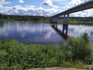 A long high concrete bridge over a wide calm river Suhona ,Russia