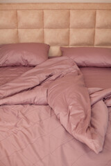 
Unmade empty bed. Bed linen is pink.