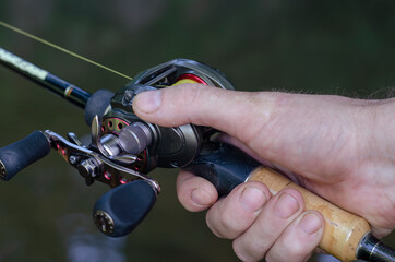 Close-up of a man's hand with bait casting rods.