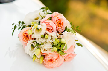 A beautiful bridal bouquet of delicate roses and other fresh flowers with wedding rings lying on them.
