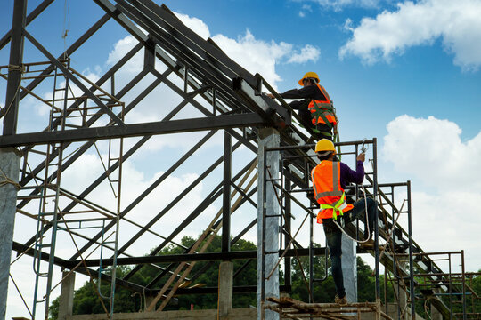 Asian worker wear safety height equipment to install the roof. Fall arrestor device for worker with hooks for safety body harness, Worker as in the construction site.