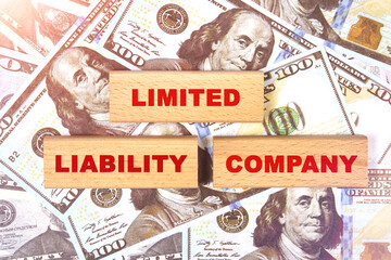 Against the background of dollar bills, the text is written on wooden blocks - limited liability company