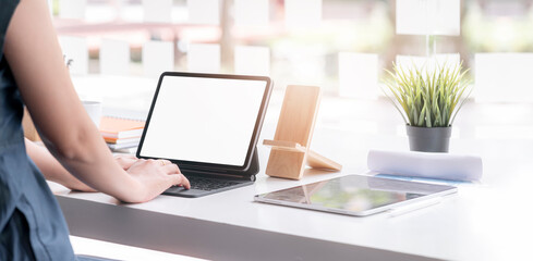 Fototapeta premium Cropped shot of woman hand typing on keyboard computer tablet while sitting at the table in co-workspace.