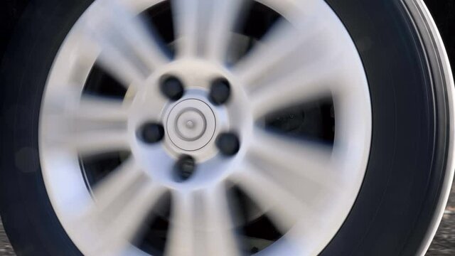 A car wheel with a shiny silver rim rides, turns to the right, to the left. Closeup