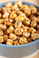 Roasted, yellow chickpeas in ceramic bowl on wooden 