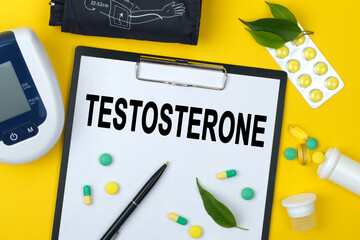 Tablet with text TESTOSTERONE. Nearby is a tonometer, medicines, vitamins and a pen.