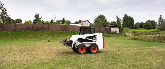 A skid steer loader clears the site for construction. Land work by the territory improvement....