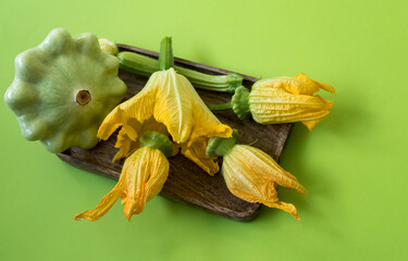 Ripe Patty Pan Squash and their yellow inflorescence on a green background