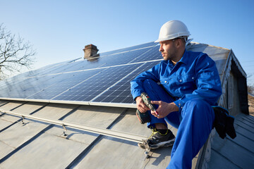 Man engineer in blue suit and protective helmet installing stand-alone solar photovoltaic panel...