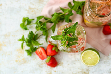 Mason jars of tasty strawberry mojito on light background