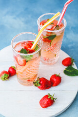 Glasses of tasty strawberry mojito on color background