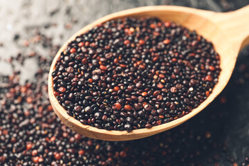 Spoon with healthy quinoa on dark background, closeup