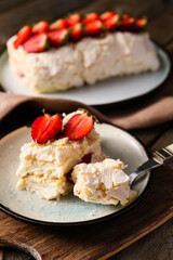 Eating of delicious meringue roll with strawberry on table, closeup