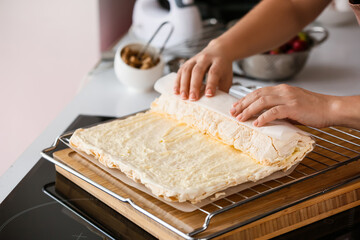 Woman preparing meringue roll in kitchen