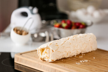 Board with meringue roll in kitchen
