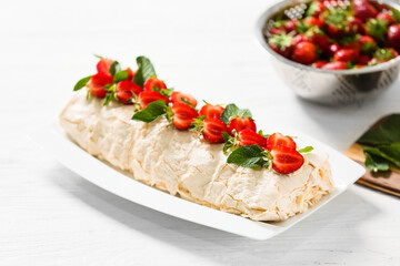 Delicious meringue roll with strawberry on table
