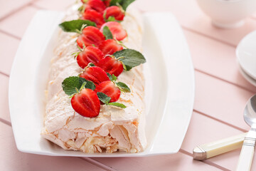 Delicious meringue roll with strawberry on table