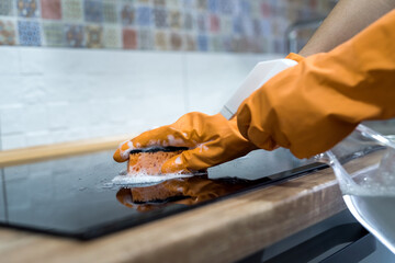 Female hand cleaning modern glass ceramic electric surface with a sponge in her kitchen
