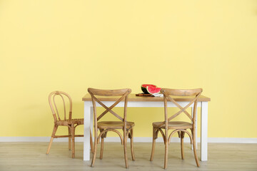 Dining table with watermelon near color wall