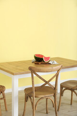 Dining table with watermelon near color wall
