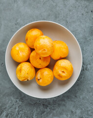 yellow plum fruit on grey concrete background with copy space