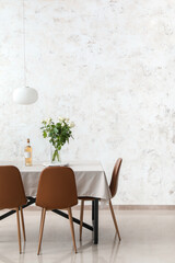 Dining table with wine and bouquet of flowers near light wall