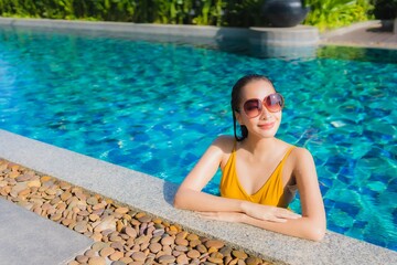 Portrait beautiful young asian woman relax happy smile around outdoor swimming pool in hotel resort
