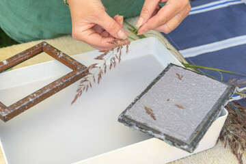 Woman holding frame for making paper sheets from waste paper pulp. Selective focus. Decorative and applied art. Recycling concept, ecology.