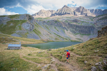 Fototapeta na wymiar boy with hat and backpack walks by the lake sabocos in the mountains of the pyrenees, on a path