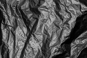 Crumpled black trash bag's surface as a backdrop texture for background.