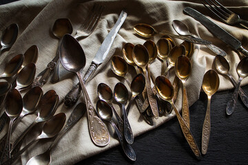 Heap of vintage retro cutlery on fabric on black background