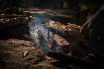 Campfire with smoke, hand throwing firewood