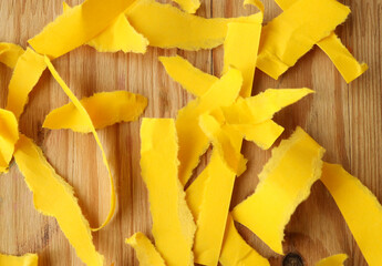 Naklejka premium torn yellow paper on a wooden table. pieces of paper are scattered over the surface.