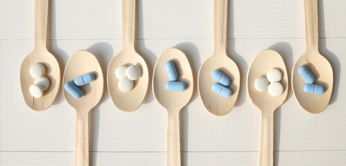 Top view Variety of vitamin and mineral tablets in a wooden spoon isolated on a white background, dietary supplements.