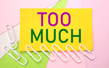 TOO MUCH. The text is written on YELLOW PAPER. on a multi-colored bright background. view from...