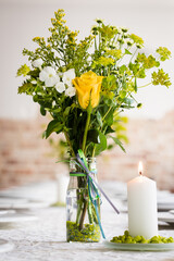 Blumenvase mit gelben Blumen als Tischdekoration