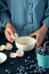 Female hand breaks egg into bowl. Bakery making. Cottage cheese casserole making.