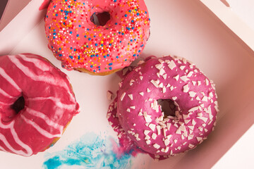 Multi-colored donuts in a white box close-up.
