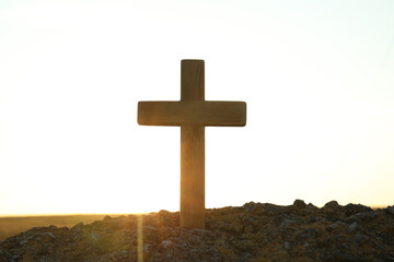 Wooden Christian cross outdoors at sunrise. Religion concept