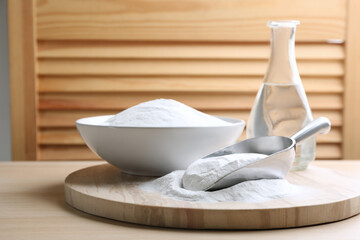 Fototapeta na wymiar Baking soda in scoop and bowl on wooden table
