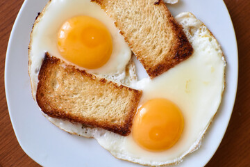 Two fried eggs with toast on a plate.