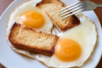 Two fried eggs with toast on a plate.