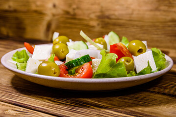 Ceramic plate with greek salad on wooden table