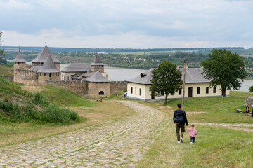 Fototapeta na wymiar Father with kid go to historical ukranian building, heritage of the country, view from the hill at rural landscape.