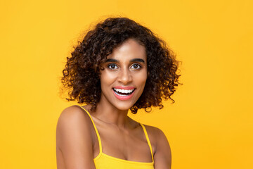 Close up portrait of smiling attractive African American woman looking in camera isolated studio yellow background