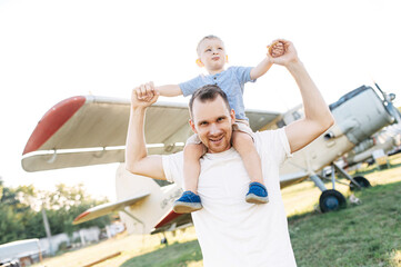 A dad and toddler spend time outdoors in an airplanes museum. A young father carries baby boy on...