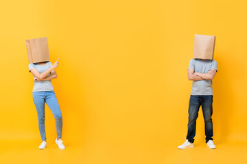 Full length portrait of faceless anonymous couple covering heads with paper bags presenting space...