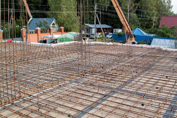 reinforcement of concrete with metal rods connected by wire. view of wooden formwork with metal holders, which will be filled with overlap between floors in country house under construction from block