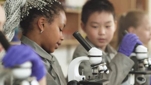 lesson in a modern school, kids look at microscopes and communicate in a chemistry lesson, the process of teaching children in a modern school.